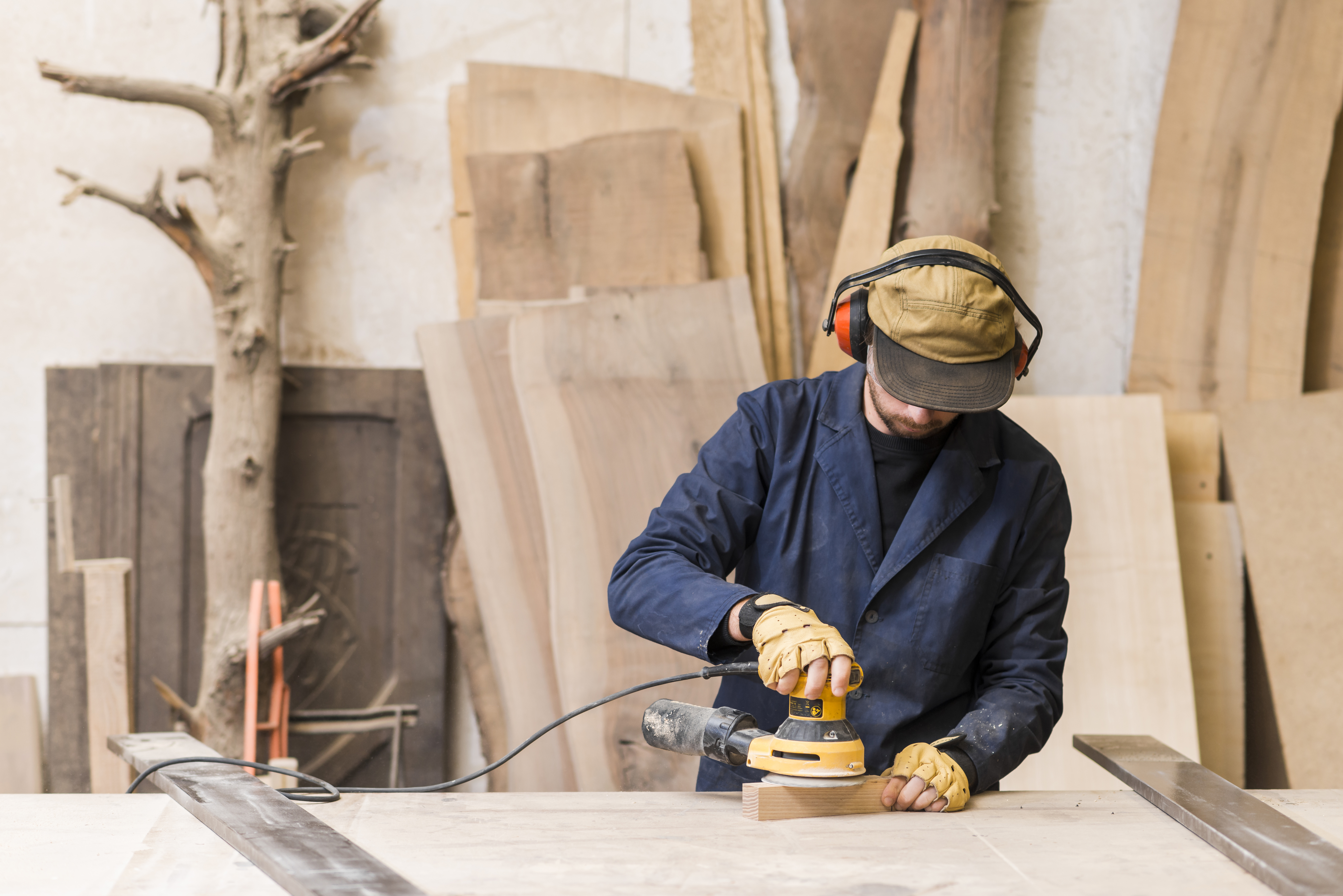 Close up van een mannelijke timmerman die elektrische schuurmachine op hout gebruikt